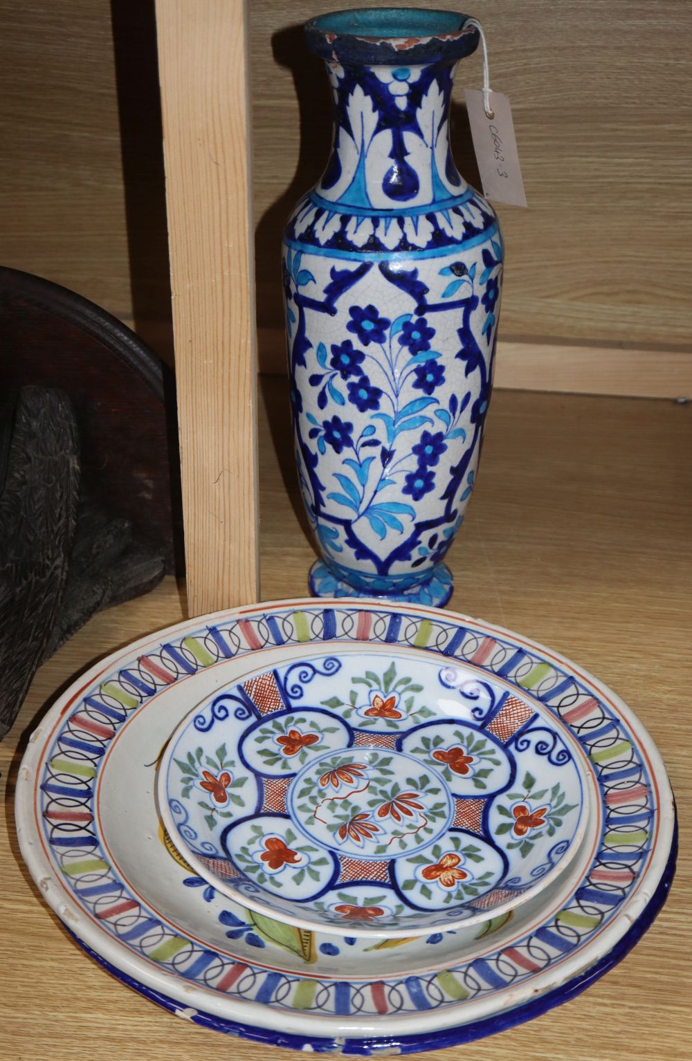 Three tin glazed earthenware dishes and a Persian stone paste vase, height 39cm